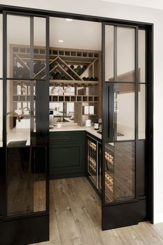 a kitchen with black cabinets and glass doors that lead to the dining room, which also has wine cellars