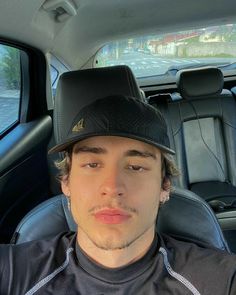 a man wearing a hat sitting in the back seat of a car