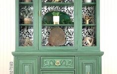 an old china cabinet painted green and decorated with gold trimmings on the doors