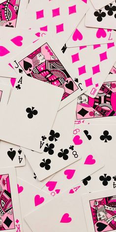 many playing cards are laying on top of each other in pink and black colors,