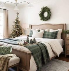 a bedroom decorated for christmas with green and white decorations on the bed, plaid throw pillows, wreaths and other holiday decor