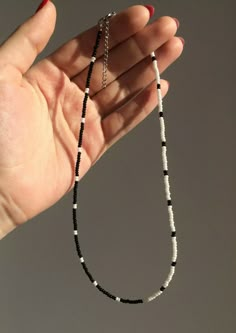 a hand holding a black and white beaded necklace in it's left hand