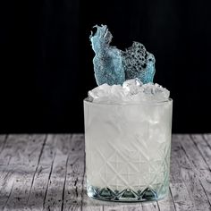 a glass filled with ice sitting on top of a wooden table