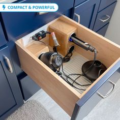 an open drawer with two hair dryers and other items in it on the floor