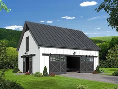 a large white barn with a black roof and two garage doors on the side of it