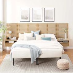 a white bed sitting on top of a wooden floor next to two pictures above it