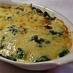 a casserole dish with cheese and spinach in it sitting on a table