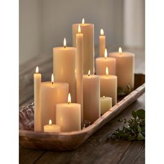 a tray filled with lots of lit candles on top of a wooden table