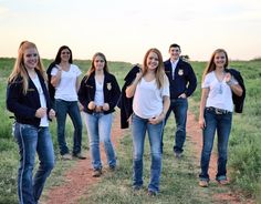 a group of young women standing next to each other on a dirt road in the grass