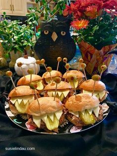 some sandwiches with toothpicks in them on a plate next to potted plants