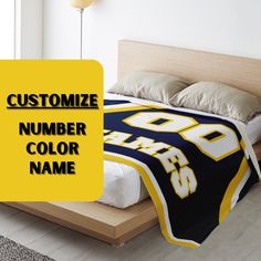 a bed with a yellow and black blanket on it that says customize number color name