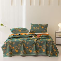 a bed covered in a green and orange comforter with matching pillow cases on it