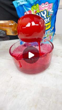 a red bowl filled with liquid next to a bag of candy