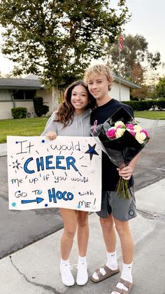 two young people standing next to each other holding flowers and a sign that says cheer