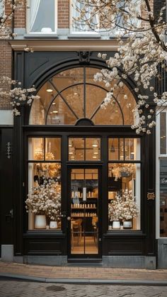 a store front with lots of windows and white flowers on the tree branches in front