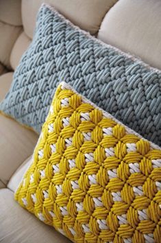 two knitted pillows sitting on top of a couch