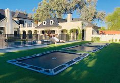 a man is jumping over an inflatable trampoline on the grass near a house