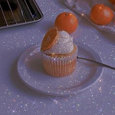 a cupcake on a plate with an orange slice and some sugar in the middle