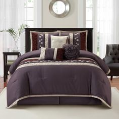 a bed with purple and white comforters in a room