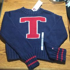 Tommy Hilfiger Sweater Is Blue With Red And White "T" On Front Chest. Ribbed Waist And Cuffs. 100% Cotton. Girl's Size Small. New With Tags. Navy Letter Print Sweater For Winter, Navy Winter Sweater For College, Navy Winter College Sweater, Preppy Cotton Winter Tops, Preppy Cotton Tops For Winter, Blue Sweater For School In Fall, Blue Fall Sweater For School, Tommy Hilfiger Cotton College Tops, Tommy Hilfiger Casual Tops For College