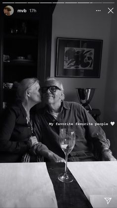 a man and woman sitting at a table with wine glasses in front of their faces