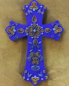 a decorative blue cross with gold accents on a tan background, hanging from the wall