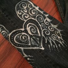 a pair of black jeans with white designs on them sitting on top of a wooden floor