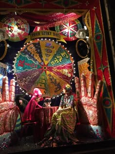 two people sitting at a table in front of an elaborate display with bright lights and decorations