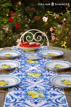 an outdoor table with plates and bowls on it