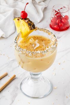 an alcoholic cocktail garnished with pineapple and sprinkles on a white table