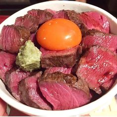 a bowl filled with meat and an egg on top