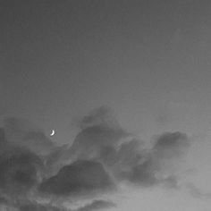 an airplane flying in the sky with clouds and a half moon behind it on a cloudy day