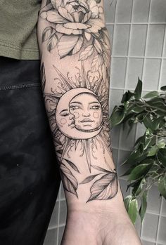 a person with a sun and moon tattoo on their arm next to a flower bush