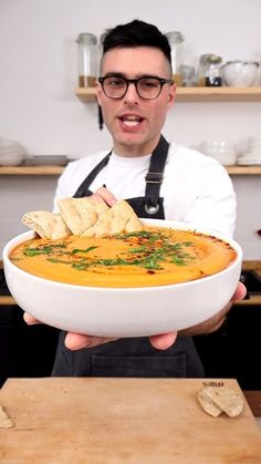 a man in an apron holding a bowl of soup