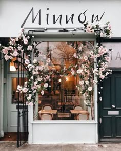 the front window of a restaurant with flowers on it's windowsill and chairs outside