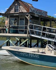 a small boat is parked in front of a house on stilts that are connected to the dock