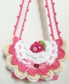 a crocheted purse with a strawberry on it hanging from a hook that is attached to the wall