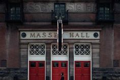 two red doors are open in front of a building with the words mass hall on it