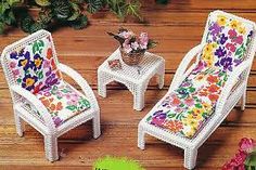 two miniature chairs and a table with flowers on the cushions are sitting next to each other