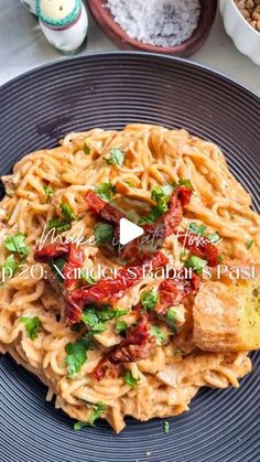 pasta with tomatoes and parsley on a black plate next to other food items in bowls