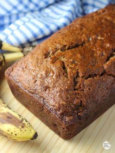 a loaf of banana bread sitting on top of a wooden cutting board next to two bananas