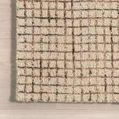 an area rug with brown and white squares on top of wooden flooring, viewed from above