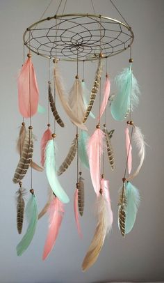 a mobile with feathers hanging from it's sides and beads on the end, in pastel colors