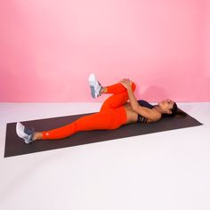 a woman in an orange outfit is doing yoga