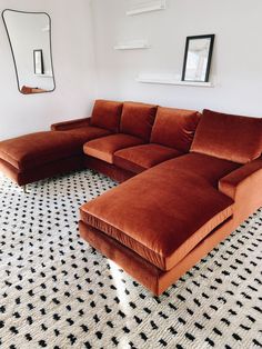 a large sectional couch sitting on top of a black and white floor next to a mirror