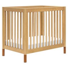 a wooden crib with white sheets on it