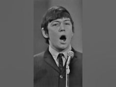 the young man is making a surprised face as he stands in front of a microphone