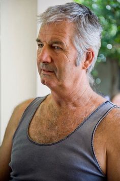 an older man wearing a tank top looking off into the distance