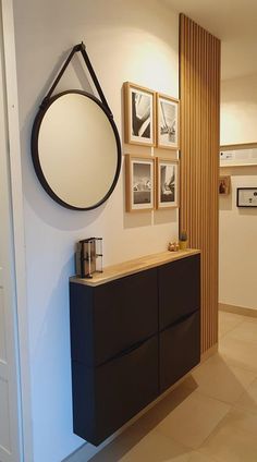 a black cabinet with a mirror and pictures on the wall above it in a hallway