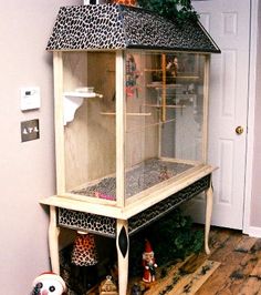 a white and black birdcage sitting on top of a wooden floor next to a door